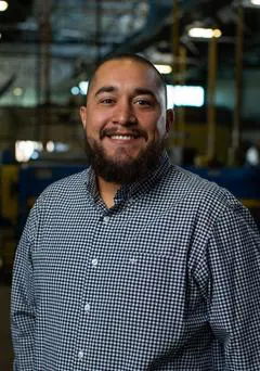 A man with beard and checkered shirt in factory.