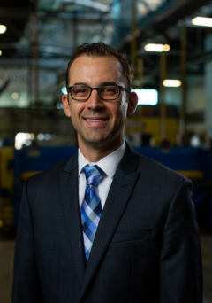 A man in a suit and tie standing inside of a warehouse.