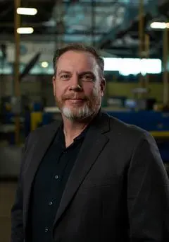 A man in a suit standing next to a machine.