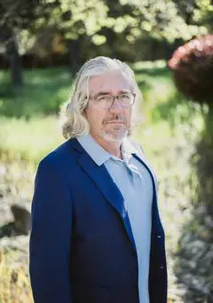 A man with long white hair and glasses.