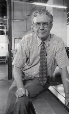 A man in glasses and a tie sitting on the ground.