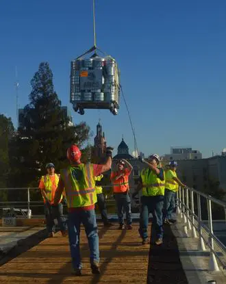 A group of construction workers standing on top of a bridge.