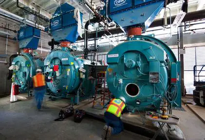 A group of workers standing next to large blue machines.